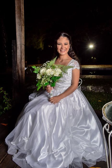 Novia con su ramo sentada en un banco de noche