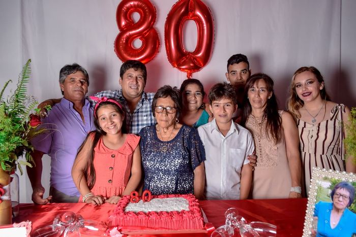 Familia reunida en un cumpleaños de 80 años con globos rojos