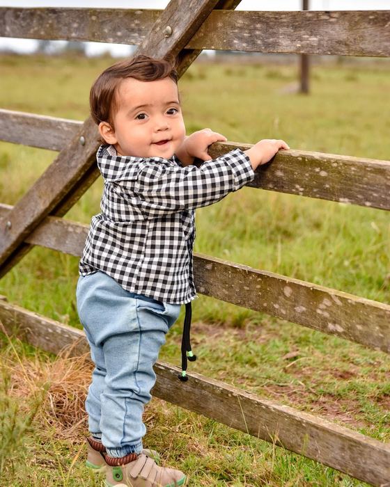 Nene apoyado en un alambrado en el campo