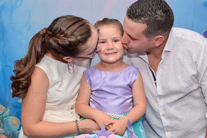 Papás besando a su hija en su cumpleaños