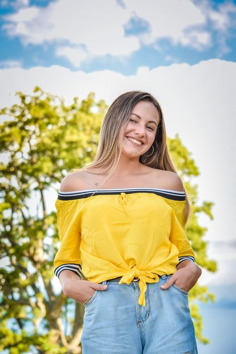 Joven con blusa amarilla sonriendo en una sesión al aire libre