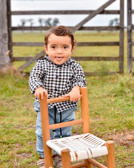 Niño parado sobre una silla de madera en el campo