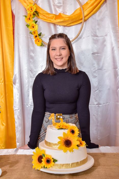 Quinceañera junto a su torta de girasoles